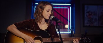 A woman is playing the guitar in front of a microphone