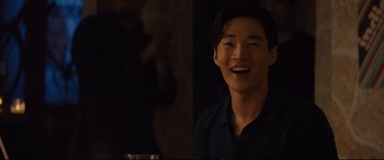 Movie still from “A Dog's Journey” (2019), directed by Gail Mancuso – A young man smiling for the camera in a dark room; Close Up shot, Over the shoulder angle