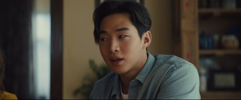 Movie still from “A Dog's Journey” (2019), directed by Gail Mancuso – A young asian man with short black hair looking to his left; Close Up shot, Over the shoulder angle