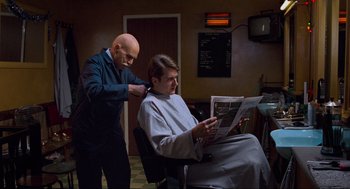 Movie still from “Eastern Promises” (2007), directed by David Cronenberg – A man sitting in front of another man in a barber shop; Medium shot, Over the shoulder angle