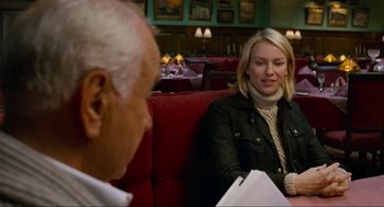 Movie still from “Eastern Promises” (2007), directed by David Cronenberg – An older man sitting next to a woman on a red couch; Medium shot, Over the shoulder angle