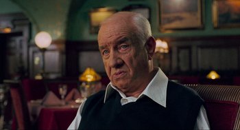 Movie still from “Eastern Promises” (2007), directed by David Cronenberg – An older man in a black vest is looking at the camera; Close Up shot, Over the shoulder angle