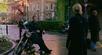 Movie still from “Eastern Promises” (2007), directed by David Cronenberg – A man sitting on the ground next to a motorcycle; Wide shot, Over the shoulder angle