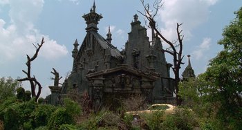 Movie still from “Edward Scissorhands” (1990), directed by Tim Burton – An old abandoned building with a tree in front of it; Extreme Wide shot, Low angle