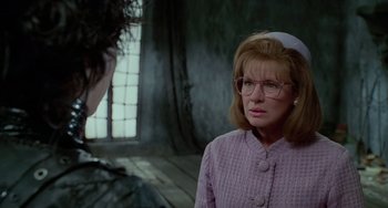 Movie still from “Edward Scissorhands” (1990), directed by Tim Burton – A woman wearing glasses and a purple sweater; Close Up shot, Over the shoulder angle