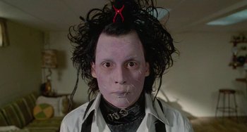 Movie still from “Edward Scissorhands” (1990), directed by Tim Burton – A man with a black hair and a white shirt and red scissor on his head; Close Up shot, Low angle