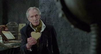 Movie still from “Edward Scissorhands” (1990), directed by Tim Burton – An older man holding a heart shaped object; Medium shot, Over the shoulder angle