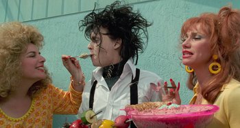 Movie still from “Edward Scissorhands” (1990), directed by Tim Burton – A woman eating food from a bowl while another woman looks on; Medium shot, Low angle