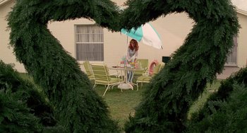 Movie still from “Edward Scissorhands” (1990), directed by Tim Burton – A woman standing at a table with an open umbrella; Extreme Wide shot, High angle