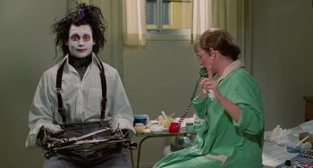 Movie still from “Edward Scissorhands” (1990), directed by Tim Burton – Two people dressed up as edward scissorhands sitting at a table; Medium shot, Over the shoulder angle