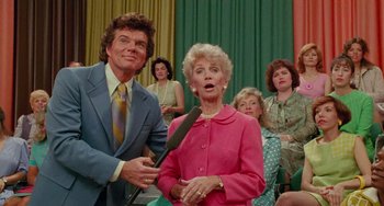 Movie still from “Edward Scissorhands” (1990), directed by Tim Burton – A group of people sitting in front of microphones in a room; Medium shot, Over the shoulder angle