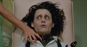 Movie still from “Edward Scissorhands” (1990), directed by Tim Burton – A woman touching the shoulder of a man with makeup on; Close Up shot, Low angle