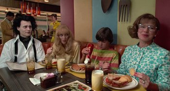 Movie still from “Edward Scissorhands” (1990), directed by Tim Burton – A group of people sitting at a table eating food; Medium shot, High angle