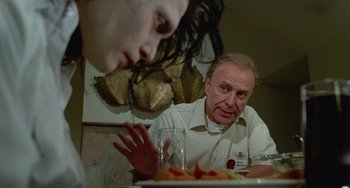 Movie still from “Edward Scissorhands” (1990), directed by Tim Burton – A man sitting at a table with a plate of food in front of him; Medium shot, Over the shoulder angle