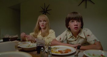 Movie still from “Edward Scissorhands” (1990), directed by Tim Burton – A couple of people sitting at a dinner table; Medium shot, Low angle