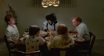 Movie still from “Edward Scissorhands” (1990), directed by Tim Burton – A group of people sitting around a table eating; Medium shot, High angle