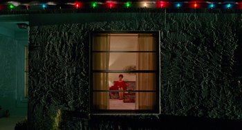 Movie still from “Edward Scissorhands” (1990), directed by Tim Burton – A man sitting on a chair looking out of a window; Extreme Wide shot, Low angle