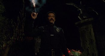Movie still from “Edward Scissorhands” (1990), directed by Tim Burton – A police officer holding a sparkler in the dark; Medium shot, Low angle