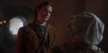 Movie still from “Ehrengard: The Art of Seduction” (2023), directed by Bille August – A man in a brown jacket and a green shirt; Medium shot, Over the shoulder angle