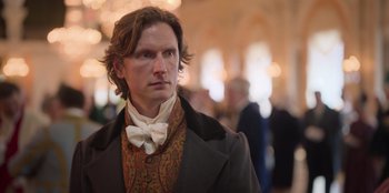 Movie still from “Ehrengard: The Art of Seduction” (2023), directed by Bille August – A person wearing a suit and bow tie; Close Up shot, Over the shoulder angle