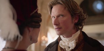 Movie still from “Ehrengard: The Art of Seduction” (2023), directed by Bille August – A person wearing a suit and tie; Close Up shot, Over the shoulder angle