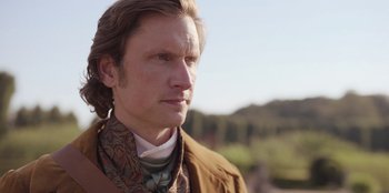 Movie still from “Ehrengard: The Art of Seduction” (2023), directed by Bille August – A person wearing a suit and tie; Close Up shot, Over the shoulder angle