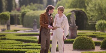 Movie still from “Ehrengard: The Art of Seduction” (2023), directed by Bille August – Two young men are talking in a garden; Medium shot, Over the shoulder angle