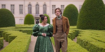 Movie still from “Ehrengard: The Art of Seduction” (2023), directed by Bille August – A man and a woman standing next to each other in front of bushes; Medium shot, Low angle