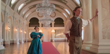 Movie still from “Ehrengard: The Art of Seduction” (2023), directed by Bille August – A man and a woman dressed in period clothing in front of chandeliers; Wide shot, Low angle