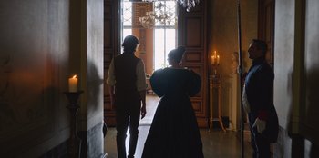 Movie still from “Ehrengard: The Art of Seduction” (2023), directed by Bille August – A man and a woman are walking through a room; Wide shot, Over the shoulder angle