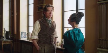 Movie still from “Ehrengard: The Art of Seduction” (2023), directed by Bille August – A man and a woman standing next to each other in a room; Medium shot, Over the shoulder angle