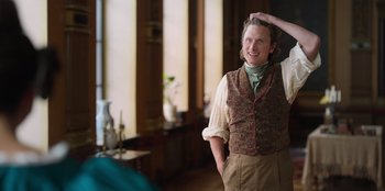 Movie still from “Ehrengard: The Art of Seduction” (2023), directed by Bille August – A man standing in front of a window with his hand on his head; Medium shot, Over the shoulder angle