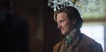 Movie still from “Ehrengard: The Art of Seduction” (2023), directed by Bille August – A person wearing a suit and tie; Close Up shot, Over the shoulder angle