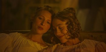 Movie still from “Ehrengard: The Art of Seduction” (2023), directed by Bille August – Two young women sitting next to each other; Close Up shot, Over the shoulder angle