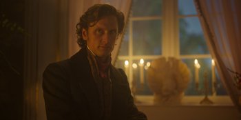 Movie still from “Ehrengard: The Art of Seduction” (2023), directed by Bille August – A man with long hair wearing a suit and tie; Close Up shot, Low angle