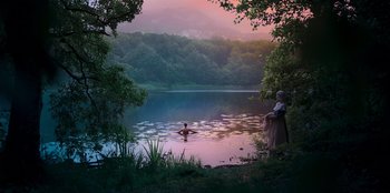 Movie still from “Ehrengard: The Art of Seduction” (2023), directed by Bille August – A man swimming in a lake surrounded by trees; Extreme Wide shot, High angle