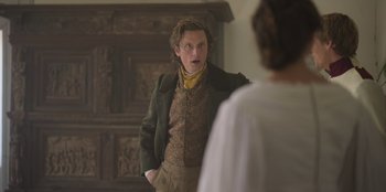 Movie still from “Ehrengard: The Art of Seduction” (2023), directed by Bille August – A man standing in front of a mirror with his hands in his pockets; Medium shot, Over the shoulder angle