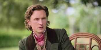 Movie still from “Ehrengard: The Art of Seduction” (2023), directed by Bille August – A person with long hair wearing a suit; Close Up shot, Over the shoulder angle