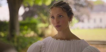 Movie still from “Ehrengard: The Art of Seduction” (2023), directed by Bille August – A beautiful young lady wearing a white dress; Close Up shot, Low angle