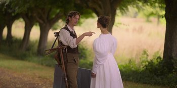 Movie still from “Ehrengard: The Art of Seduction” (2023), directed by Bille August – A man and a woman are standing in a field; Medium shot, Over the shoulder angle