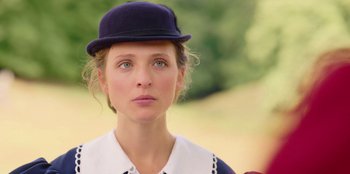 Movie still from “Ehrengard: The Art of Seduction” (2023), directed by Bille August – A woman wearing a hat and a white shirt; Close Up shot, Over the shoulder angle
