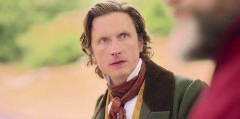 Movie still from “Ehrengard: The Art of Seduction” (2023), directed by Bille August – A person wearing a suit and tie; Close Up shot, Over the shoulder angle