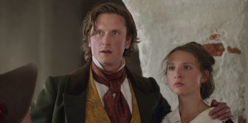 Movie still from “Ehrengard: The Art of Seduction” (2023), directed by Bille August – A man and a woman standing next to each other; Close Up shot, Low angle