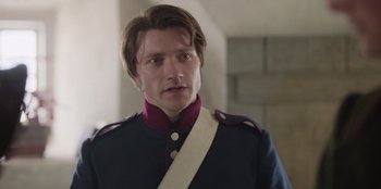 Movie still from “Ehrengard: The Art of Seduction” (2023), directed by Bille August – A man in a military uniform looking at the camera; Close Up shot, Over the shoulder angle