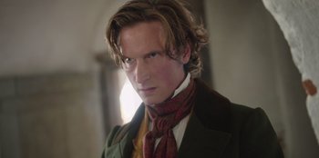 Movie still from “Ehrengard: The Art of Seduction” (2023), directed by Bille August – A person wearing a suit and tie; Close Up shot, Over the shoulder angle