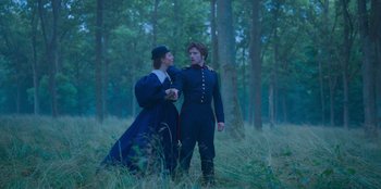 Movie still from “Ehrengard: The Art of Seduction” (2023), directed by Bille August – A man and a woman standing next to each other in the woods; Medium shot, Low angle