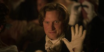 Movie still from “Ehrengard: The Art of Seduction” (2023), directed by Bille August – A person wearing a suit and a bow tie; Close Up shot, Over the shoulder angle