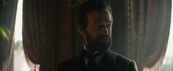 Movie still from “Eiffel” (2021), directed by Martin Bourboulon – A man with a beard and a suit and tie; Close Up shot, Over the shoulder angle