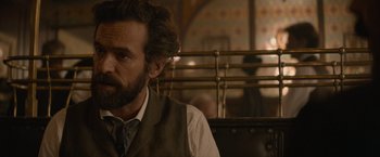 Movie still from “Eiffel” (2021), directed by Martin Bourboulon – A man with a beard wearing a vest and a tie; Close Up shot, Over the shoulder angle