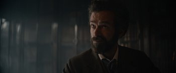 Movie still from “Eiffel” (2021), directed by Martin Bourboulon – A man with a goatee and a beard looking to his left; Close Up shot, Over the shoulder angle
